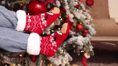 Yılbaşı ağacının arka planında parlak çoraplı bacaklar. Sıcak Noel yün çorapları. Noel atmosferi. Kız evde dinleniyor. Kış, yeni yıl konsepti. Şenlikli Yeni Yıl giysileri