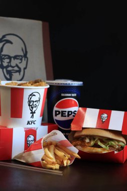 Kyiv, Ukrayna - 20 Ekim 2024: KFC. Striptiz kovası, burger, standart patates kızartması, Peps ve bir kese kağıdı. KFC fast food restoranı. Karanlık bir arka planda fast food. KFC 'de özelleştirilmiş menü ögeleri