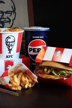 Kyiv, Ukrayna - 20 Ekim 2024: KFC. Striptiz kovası, burger, standart patates kızartması, Peps ve bir kese kağıdı. KFC fast food restoranı. Karanlık bir arka planda fast food. KFC 'de özelleştirilmiş menü ögeleri