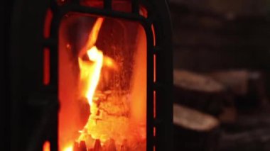 Modern odun ocağı şöminesi. Şöminede yangın var, yakın plan. Şömine rahatlık ve konfor yaratır, akşam ya da gece. Karanlıkta şöminede yanan ateş alevi. Sıcak ışık