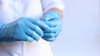 Mavi tıbbi eldivenli kadın elleri, yakın plan. Doktor ya da hemşire, üniformalı. Mavi eldivenli ve beyaz ceketli doktor. Sağlık çalışanı. Kadın eli yakın çekim, nitril, lastik, tıbbi eldiven.