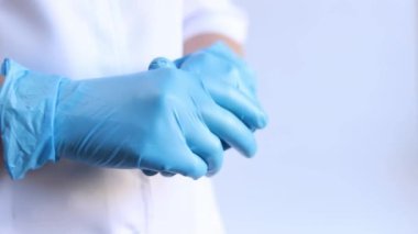 Mavi tıbbi eldivenli kadın elleri, yakın plan. Doktor ya da hemşire, üniformalı. Mavi eldivenli ve beyaz ceketli doktor. Sağlık çalışanı. Kadın eli yakın çekim, nitril, lastik, tıbbi eldiven.