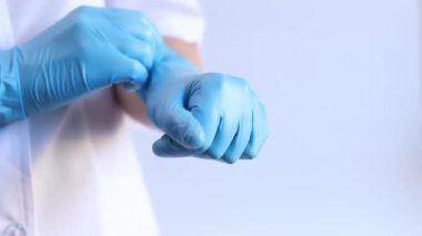 Mavi tıbbi eldivenli kadın elleri, yakın plan. Doktor ya da hemşire, üniformalı. Mavi eldivenli ve beyaz ceketli doktor. Sağlık çalışanı. Kadın eli yakın çekim, nitril, lastik, tıbbi eldiven.