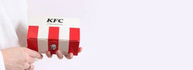 Kyiv, Ukrayna - 15 Aralık 2024: KFC fast food karton kutusu. Popüler fast food zinciri Kentucky Fried Chicken. KFC karton kutu tutan kadın eller, yakın plan, açık arkaplan