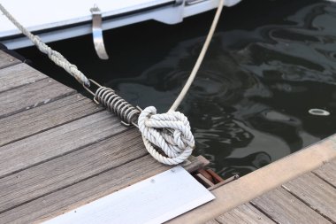 Demirleme kalesi, bir yat iskelesinde bağlama düğümü. Yatın bağlama ipleri diz kapağına bağlı. Halatları bağlamak için iskelede diz çökün. Bağlama ve bağlama ipleri için diz çökün