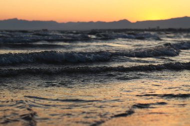 Denizde gün batımı. Balear Denizi 'nde güzel bir gün batımı manzarası. Küçük dalgalarla deniz manzarası. Dalgaların deniz manzarası daha alçak bir açıdan. Salou, İspanya