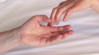 Eşcinsel ilişkiler, lezbiyenler. Eşcinsel evlilik ve aşk kavramı. Mutlu lezbiyen çift. Beyaz çarşaflar üzerinde birbirine dokunan iki kadın eli. Yatakta iki kadın eli var. Yakın plan. LGBTQ