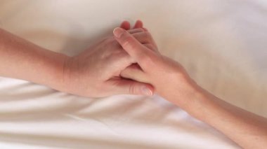 Eşcinsel ilişkiler, lezbiyenler. Eşcinsel evlilik ve aşk kavramı. Mutlu lezbiyen çift. Beyaz çarşaflar üzerinde birbirine dokunan iki kadın eli. Yatakta iki kadın eli var. Yakın plan. LGBTQ