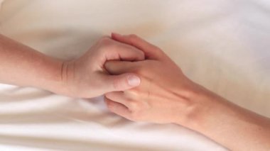 Eşcinsel ilişkiler, lezbiyenler. Eşcinsel evlilik ve aşk kavramı. Mutlu lezbiyen çift. Beyaz çarşaflar üzerinde birbirine dokunan iki kadın eli. Yatakta iki kadın eli var. Yakın plan. LGBTQ