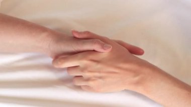 Eşcinsel ilişkiler, lezbiyenler. Eşcinsel evlilik ve aşk kavramı. Mutlu lezbiyen çift. Beyaz çarşaflar üzerinde birbirine dokunan iki kadın eli. Yatakta iki kadın eli var. Yakın plan. LGBTQ
