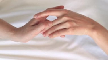 Eşcinsel ilişkiler, lezbiyenler. Eşcinsel evlilik ve aşk kavramı. Mutlu lezbiyen çift. Beyaz çarşaflar üzerinde birbirine dokunan iki kadın eli. Yatakta iki kadın eli var. Yakın plan. LGBTQ