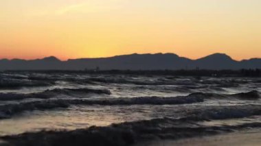 Denizde gün batımı, sahilde dalgalar. Bolerya Denizi 'nin güzel manzarası. Küçük dalgalarla deniz manzarası. Dalgaların deniz manzarası daha alçak bir açıdan. Salou, İspanya