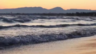 Denizde gün batımı, sahilde dalgalar. Bolerya Denizi 'nin güzel manzarası. Küçük dalgalarla deniz manzarası. Dalgaların deniz manzarası daha alçak bir açıdan. Salou, İspanya