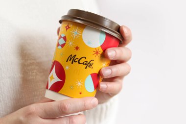 Kyiv, Ukrayna - 19 Aralık 2024: McDonalds 'dan Noel kahvesi. Beyaz arka planda McDonald 's' tan bir fincan kahve tutan bir kadın. McDonald 's fast food restoranı. McCafe 'de. İç.