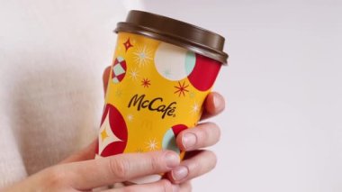 Kyiv, Ukrayna - 19 Aralık 2024: McDonalds 'dan Noel kahvesi. Beyaz arka planda McDonald 's' tan bir fincan kahve tutan bir kadın. McDonald 's fast food restoranı. McCafe 'de. İç.