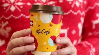 Kyiv, Ukrayna - 19 Aralık 2024: McDonalds 'dan Noel kahvesi. Kırmızı Noel kazaklı kadın elinde McDonald 's' tan bir fincan kahve tutuyor. McDonald 's fast food restoranı. McCafe içkisi