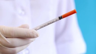 İnsülin şırıngası. Şırıngalı hemşire ya da doktor. Mavi arka planda şırınga tutan eldivenli kadın, yakın plan. Diyabet iğneleri için insülin şırıngası. Diyabet tedavisi görüyor. İlaç.