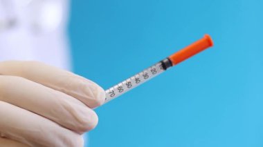 İnsülin şırıngası. Şırıngalı hemşire ya da doktor. Mavi arka planda şırınga tutan eldivenli kadın, yakın plan. Diyabet iğneleri için insülin şırıngası. Diyabet tedavisi görüyor. İlaç.