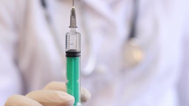 Şırıngalı hemşire ya da doktor, mavi arkaplan. Lateks eldivenli kadın elinin elinde şırınga var. Şırıngalı hemşire ya da doktor, yakın plan. Aşılama. Enjeksiyon. İlaç.