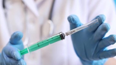Şırıngalı hemşire ya da doktor, mavi arkaplan. Lateks eldivenli kadın elinin elinde şırınga var. Şırıngalı hemşire ya da doktor, yakın plan. Aşılama. Enjeksiyon. İlaç.
