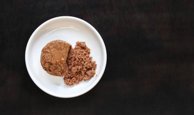 Kedi maması, börek, güzel manzara. Siyah arka planda yuvarlak beyaz bir tabakta evcil hayvanlar için konserve yiyecekler. Evcil kediler için lezzetli ve sağlıklı yiyecekler. Bir porsiyon ıslak yemek, tabakta bir kedi için yumuşak ezme. Boşluğu kopyala
