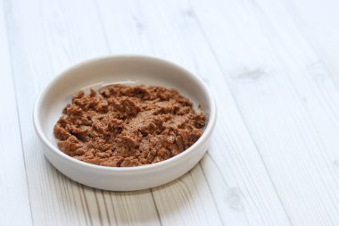 Kedi maması, börek, yan görüş. Hafif ahşap arka planda yuvarlak beyaz bir tabakta konserve evcil hayvan yiyeceği. Evcil kediler için lezzetli ve dengeli yiyecekler. Islak yiyecek porsiyonu, tabakta kedi için yumuşak börek.