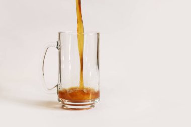 Arka planda hafif bir fincana kvass dökmek, yakın plan. Gri arka planda bir bardak bira ya da kvass. Saplı geleneksel bir bira bardağı. Soğuk, lezzetli bir içecekle doldurulan bardağa yakın plan.