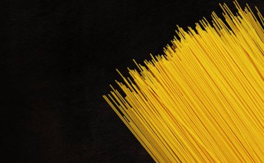 Koyu tahta arka planda çiğ spagetti. Durum buğday spagettisi. Kuru spagetti, üst manzara. Pişmemiş sarı makarna. Bir yığın spagetti, siyah masada çiğ İtalyan makarnası.