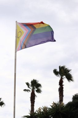 Salou, Spain - September 18, 2024: Intersex-inclusive redesign of the Progress Pride Flag. Rainbow LGBT flag against the sky. Flag flutters in the wind in bad weather clipart