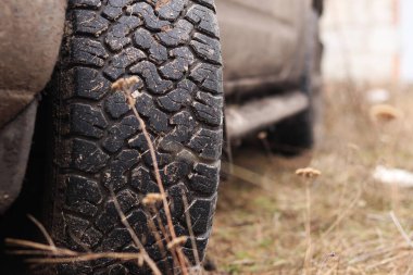 Çamurda kamyonet, off-road lastikleri, yakın plan. Toprak yolda araba tekerleği, kuru çimenler. Kamyonetin kenarına çamur sıçramış. Macera, sonbaharda açık havada. Off-road aracı, macera. Kamyonet basamağı.