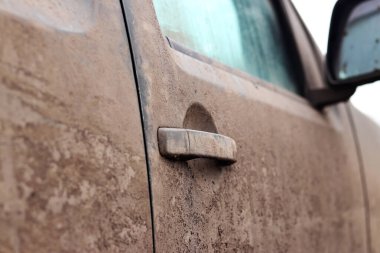 Arabanın kapı kolu çamurda, yakın plan. Çamurda kamyonet, kamyonetin yanına çamur sıçramış. Bataklık arazisinde sürdükten sonra kirli araba. Kuru çamurla kaplı bir arabanın kapı kolu.