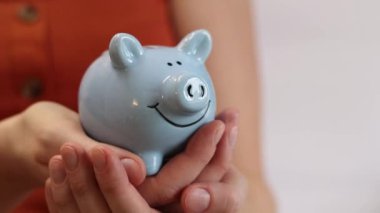 Kumbarayı tutan kadın eller, yakın plan. Yazlık elbiseli bir kız kumbarayı elinde tutuyor. Tasarruf ve mali planlama kavramı. Şirin kumbara.