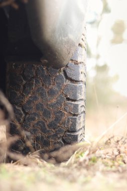 Çamurda kamyonet, off-road lastikleri, yakın plan. Toprak yolda araba tekerleği, kuru çimenler. Kamyonetin kenarına çamur sıçramış. Macera, sonbaharda açık havada. Off-road aracı, macera. Kamyonet basamağı.
