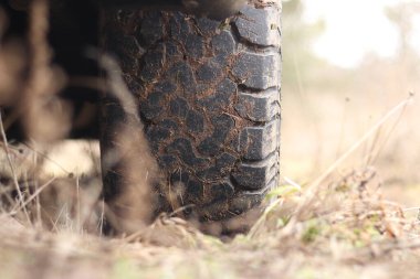 Çamurda kamyonet, off-road lastikleri, yakın plan. Toprak yolda araba tekerleği, kuru çimenler. Kamyonetin kenarına çamur sıçramış. Macera, sonbaharda açık havada. Off-road aracı, macera. Kamyonet basamağı.