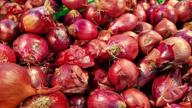 Süpermarkette kırmızı soğan yakın plan. Marketteki plastik yeşil kutuda bir sürü kırmızı soğan var. Çiftçi pazarında yeşil plastik kutuda soğanlar. Dükkanda satılık soğanlar