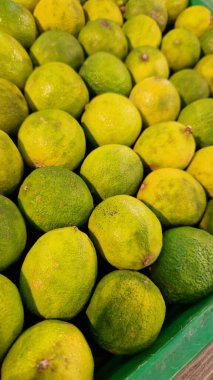 Seçici odaklı limonlar. Mağazada satılık tonlarca lezzetli limon. Taze ürünlerin çeşitliliği. Süpermarkette satılık limonlar. Olgun, sulu, yeşil meyveli C vitamini.