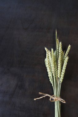 Tahta arka planda bir buğday demeti, üst manzara. Koyu ahşap arka plan ve buğday kulakları. Hasat konsepti. Uzayı kopyala Metin için boş alan. Mısır gevreği. Bir demet buğday kulağı. Hasat simgesi