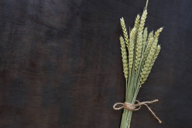 Tahta arka planda bir buğday demeti, üst manzara. Koyu ahşap arka plan ve buğday kulakları. Hasat konsepti. Uzayı kopyala Metin için boş alan. Mısır gevreği. Bir demet buğday kulağı. Hasat simgesi