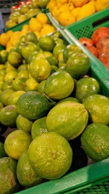 Seçici odaklı limonlar. Mağazada satılık tonlarca lezzetli limon. Taze ürünlerin çeşitliliği. Süpermarkette satılık limonlar. Olgun, sulu, yeşil meyveli C vitamini.