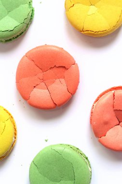 Açık arkaplanlı, parlak renkli Fransız kurabiyeleri, üst manzara. Farklı aromalı makaron çeşitleri. Lezzetli hamur işleri. Buruşuk badem kurabiyeleri, düz yatış. Beyaz arkaplanda kırık makarna