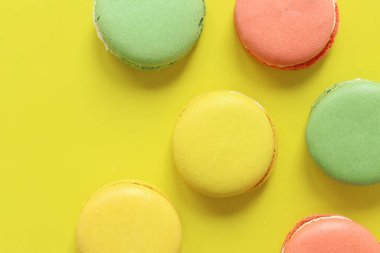 Sarı arka planda parlak Fransız badem kurabiyeleri, üst manzara. Farklı aromalı çok renkli badem kurabiyesi çeşitleri. Lezzetli hamur işleri, düz yatak. Yemek arkaplanı. Tatlılar