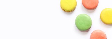 Beyaz arka planda tatlı renkli makaronlar. Lezzetli hamur işleri, düz yatak. Yemek arkaplanı. Şekerler. Beyaz arka planda parlak Fransız badem kurabiyeleri, üst manzara. Renkli badem kurabiyesi çeşitleri