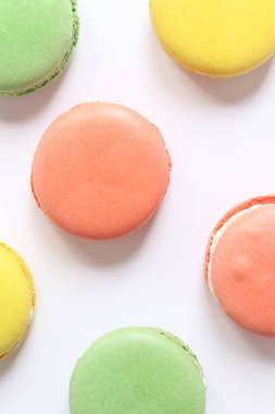 Beyaz arka planda tatlı renkli makaronlar. Lezzetli hamur işleri, düz yatak. Yemek arkaplanı. Şekerler. Beyaz arka planda parlak Fransız badem kurabiyeleri, üst manzara. Renkli badem kurabiyesi çeşitleri