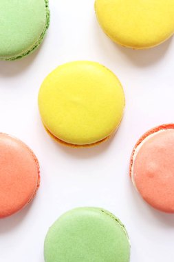 Beyaz arka planda tatlı renkli makaronlar. Lezzetli hamur işleri, düz yatak. Yemek arkaplanı. Şekerler. Beyaz arka planda parlak Fransız badem kurabiyeleri, üst manzara. Renkli badem kurabiyesi çeşitleri