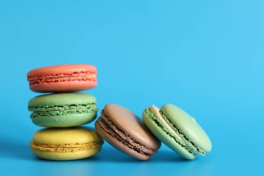 Çok sayıda renkli badem kurabiyesi yakından çekilmiş. Mavi arka planda parlak Fransız badem kurabiyeleri, yan manzara. Farklı aromalı makaron çeşitleri. Lezzetli hamur işleri, kurabiyeler, yemek geçmişi. Bir yığın tatlı.