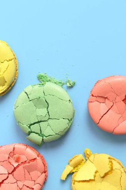 Crumpled macarons, flat lay. Broken macaron on blue background. Bright multi-colored French macarons on a blue background, top view. Assortment of macarons with different flavors. Delicious pastries clipart