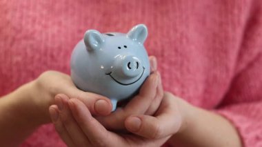 Bozuk paralar için mavi kumbara yakın plan. Tarz sahibi domuz kumbaralı kadın elleri. Tasarruf kavramı. Planlama masrafları, gelecek için tasarruf