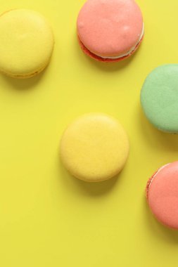 Sarı arka planda parlak Fransız badem kurabiyeleri, üst manzara. Farklı aromalı çok renkli badem kurabiyesi çeşitleri. Lezzetli hamur işleri, düz yatak. Yemek arkaplanı. Tatlılar