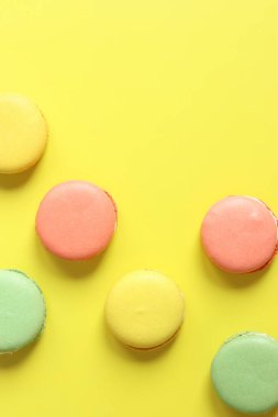 Sarı arka planda parlak Fransız badem kurabiyeleri, üst manzara. Farklı aromalı çok renkli badem kurabiyesi çeşitleri. Lezzetli hamur işleri, düz yatak. Yemek arkaplanı. Tatlılar