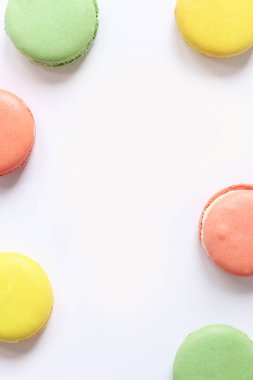 Beyaz arka planda tatlı renkli makaronlar. Lezzetli hamur işleri, düz yatak. Yemek arkaplanı. Şekerler. Beyaz arka planda parlak Fransız badem kurabiyeleri, üst manzara. Renkli badem kurabiyesi çeşitleri